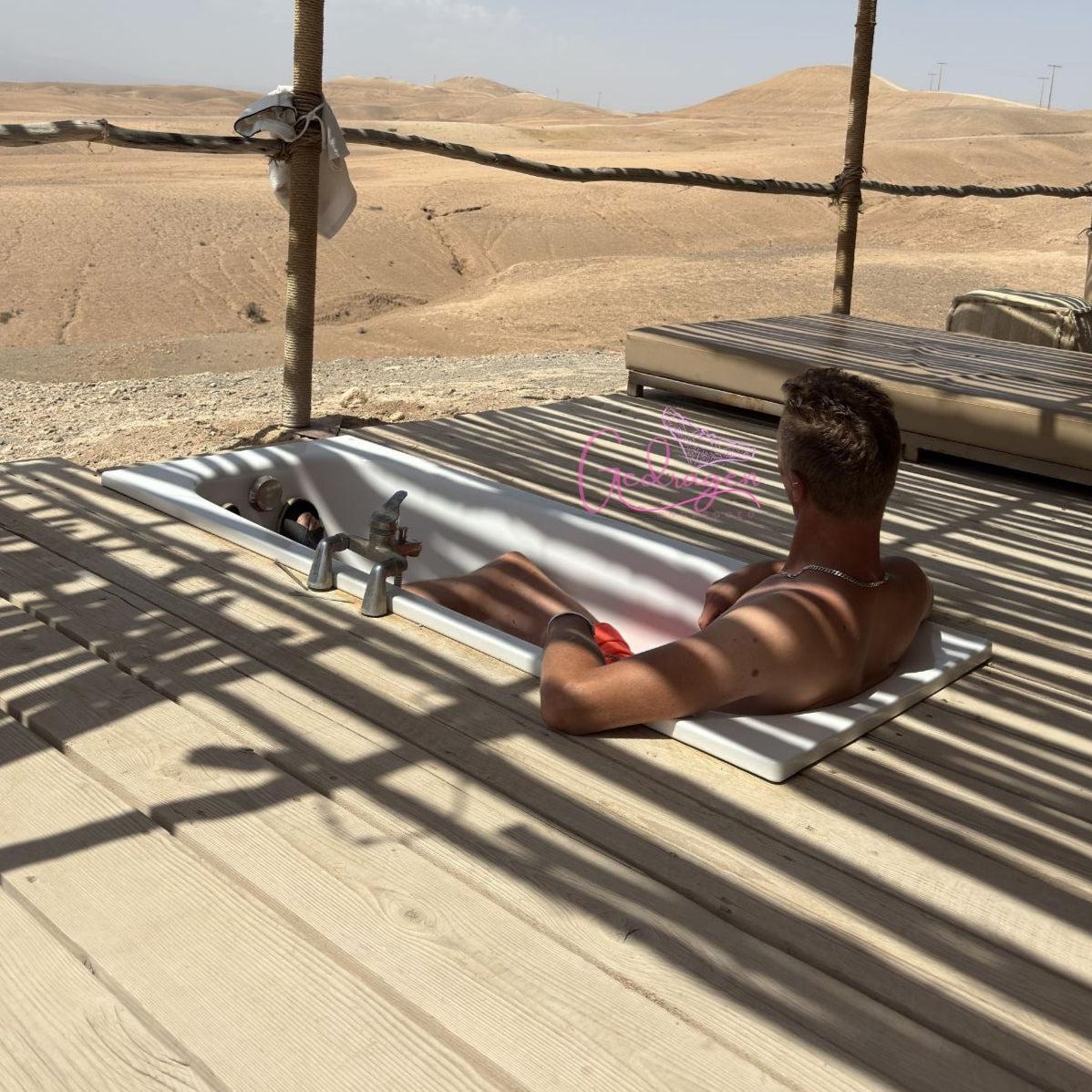 Ontspannen moment man ligt in een buitenbad met uitzicht over de woestijn, pure rust en vrijheid.